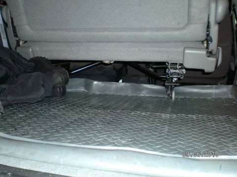 1996 Ford Bronco - View of a gray cloth rear bench seat's underside from the cargo area, showing the black tubular seat frame, latch mechanism and mounting ha…