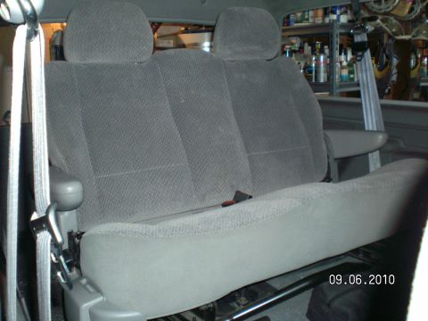 1996 Ford Bronco - Gray cloth minivan-style rear bench seat with two headrests and a fold-down armrest, fitted inside a vehicle's rear compartment with seat b…