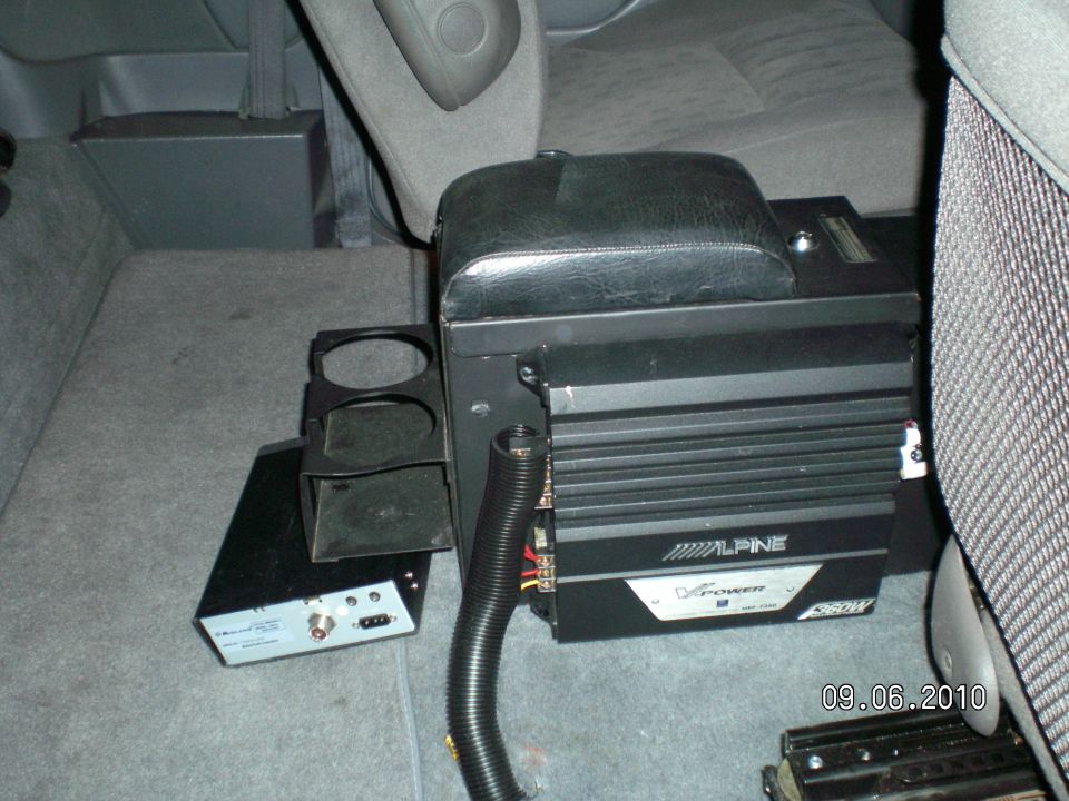 Alpine V-Power 550W amp mounted on floor console in gray cloth vehicle interior