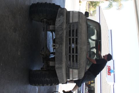 1992 Ford Bronco - A mud-covered 1992 Ford Bronco is seen from the front, equipped with large off-road tires.