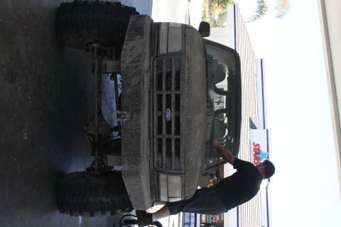 1992 Ford Bronco - A man is working on the front of a heavily modified Ford truck, which appears to be a Bronco.
