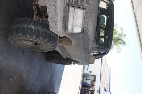 1992 Ford Bronco - Mud-covered 1992 Ford Bronco with aggressive off-road tires parked outdoors.