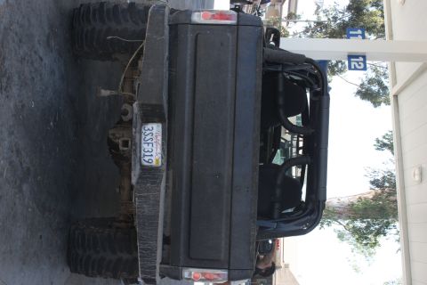 1992 Ford Bronco - This modified SUV features oversized tires and an external roll cage, seen from the rear with a California license plate.