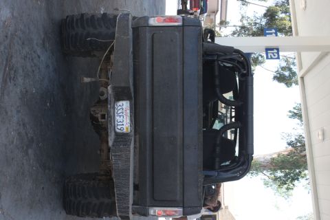1992 Ford Bronco - Rear view of a black SUV modified with a roll cage and oversized tires, parked outdoors.