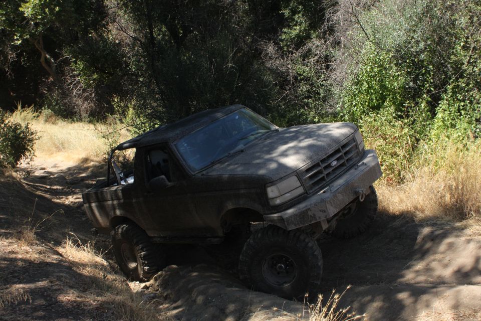 1992 Ford Bronco navigating a steep dirt path with brush on either side
