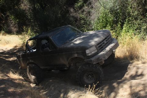 1992 Ford Bronco - A 1992 Ford Bronco navigates a challenging off-road trail with steep inclines and loose dirt.