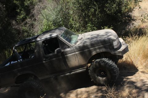 1992 Ford Bronco - This 1992 Ford Bronco navigates a dusty, off-road trail, its body coated in mud.