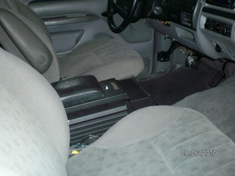 1996 Ford Bronco - Vehicle interior with front seats and center console visible, an aftermarket stereo amplifier.