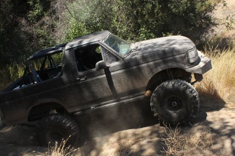 1992 Ford Bronco - A heavily modified 1992 Ford Bronco navigates a dusty, off-road trail.