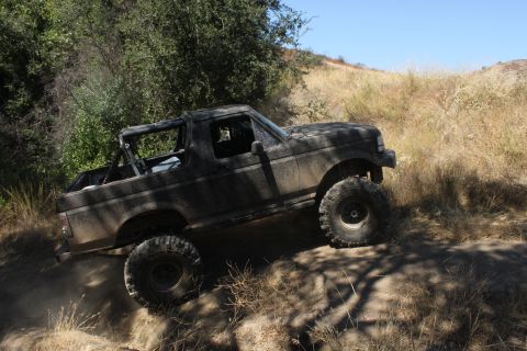 1992 Ford Bronco - This lifted 1992 Ford Bronco navigates a challenging dirt path, kicking up dust as it goes.