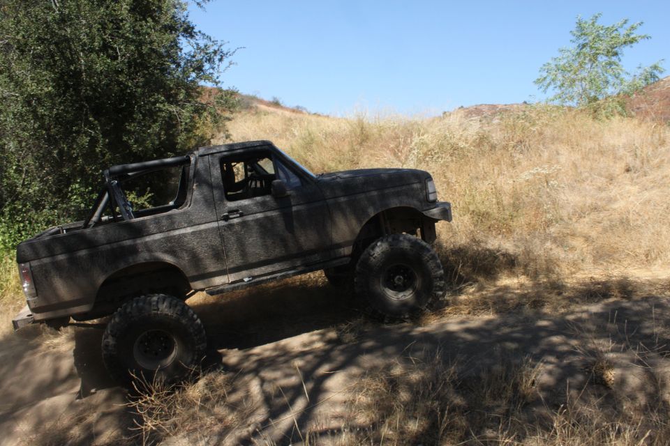 Dark gray Ford Bronco with large off-road tires on a dirt trail