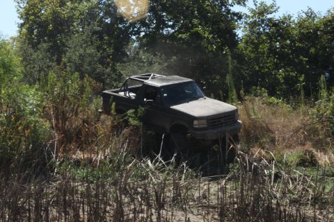 1992 Ford Bronco - A lifted Ford F-Series truck navigates through overgrown vegetation.
