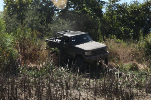 1992 Ford Bronco - A 1992 Ford Bronco navigates a rough, overgrown trail.