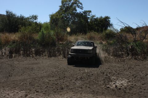 1992 Ford Bronco - This 1992 Ford Bronco navigates a muddy trail with trees and brush in the background.