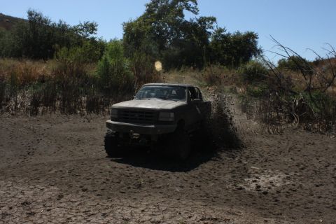 1992 Ford Bronco - A 1992 Ford Bronco kicks up mud as it drives through a muddy trail.