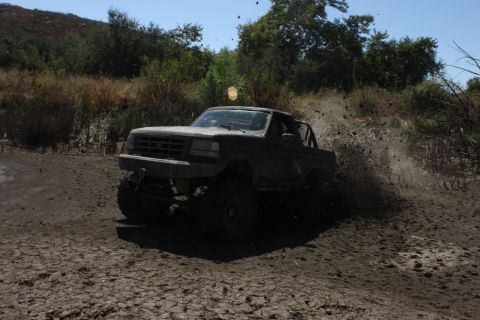 1992 Ford Bronco - This 1992 Ford Bronco is navigating a muddy trail with significant splash.