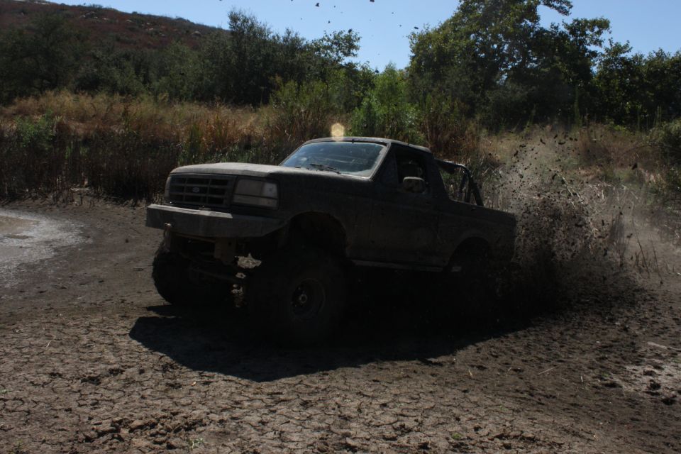 Ford Bronco driving through mud, kicking up dirt