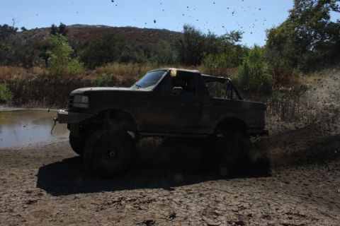 1992 Ford Bronco - This 1992 Ford Bronco is navigating a muddy trail with significant splashing.