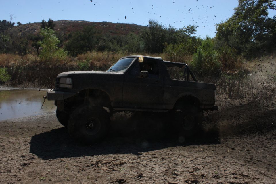 1992 Ford Bronco driving through mud, side view