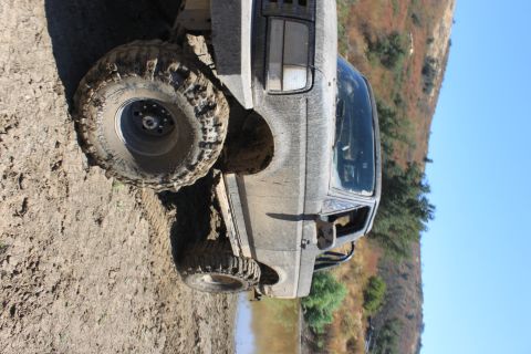 1992 Ford Bronco - This 1992 Ford Bronco is shown off-road, covered in mud, with a clear blue sky in the background.