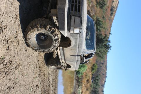 1992 Ford Bronco - Muddy 1992 Ford Bronco with large tires near water on an off-road trail.