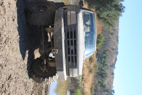 1992 Ford Bronco - This 1992 Ford Bronco is shown in a front view, covered in mud, on a dirt trail.
