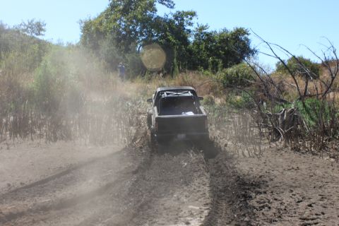 1992 Ford Bronco - A truck navigates a challenging muddy terrain on a sunny day.