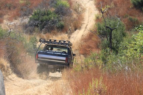 1992 Ford Bronco - Ford Bronco navigates a steep, dry dirt path surrounded by brush.