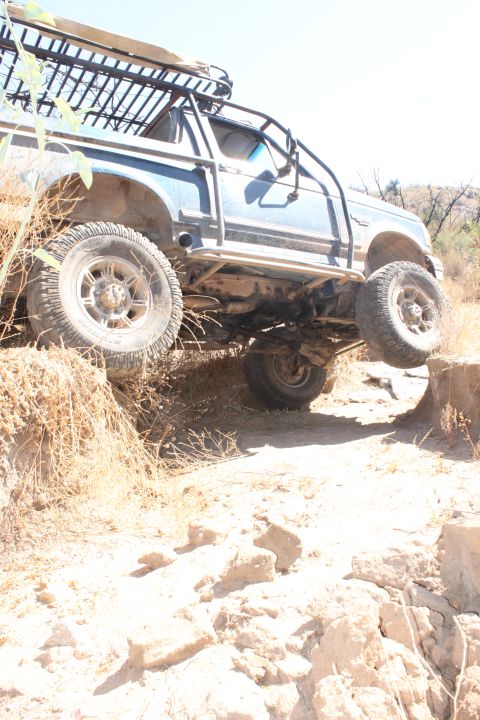 1992 Ford Bronco - An off-road SUV navigates a challenging dirt path, demonstrating its suspension capabilities.