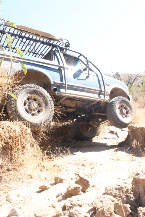 1992 Ford Bronco - This 1992 Ford Bronco navigates a challenging dirt trail, its off-road capabilities with a side view and roof rack.