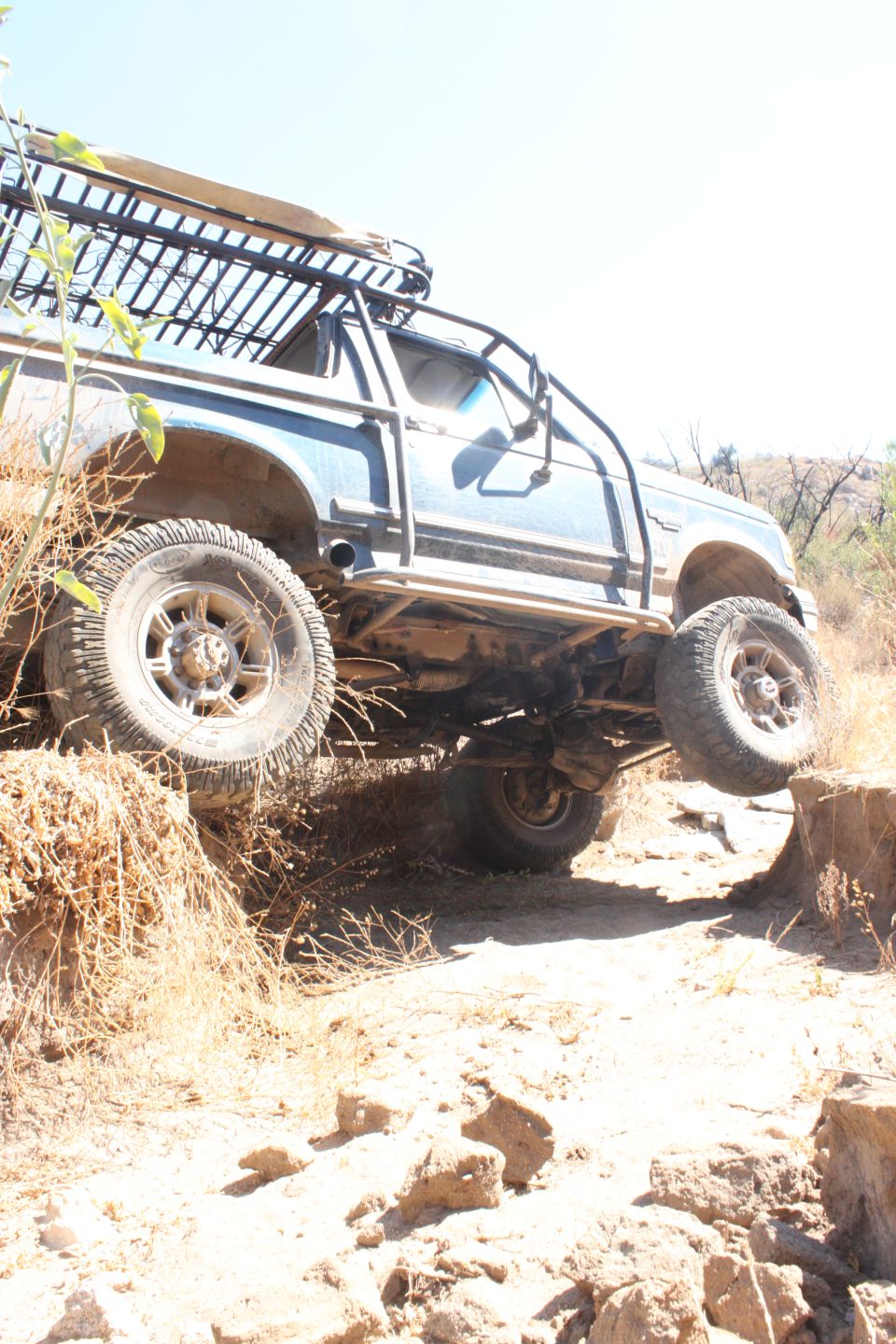 1992 Ford Bronco off-roading, side view, blue with roof rack