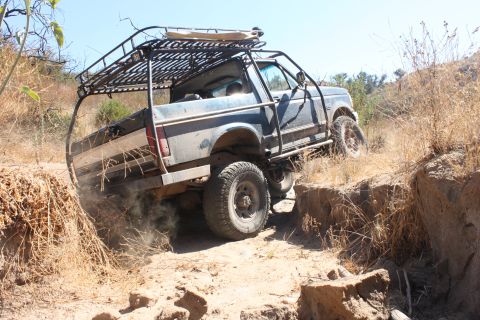 1992 Ford Bronco - This modified 1992 Ford Bronco tackles a challenging off-road course with a custom roll cage and roof rack.