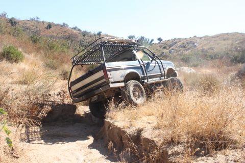 1992 Ford Bronco - This 1992 Ford Bronco is tackling a challenging off-road trail with a custom roll cage and rack.