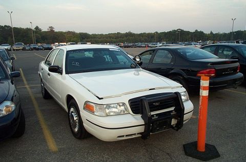 2001 Ford Crown Victoria - White Ford Crown Victoria police sedan photographed from the front three-quarter in an auction lot, fitted with a black tubular push bumper…