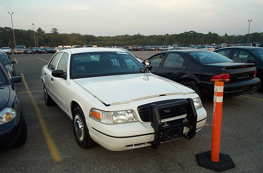 White Ford Crown Victoria police sedan with black push bumper in an auction parking lot