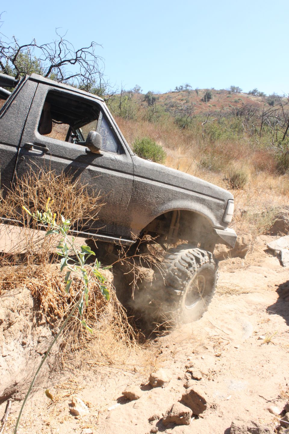 1992 Ford Bronco driving off-road, kicking up dust