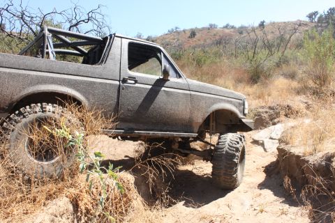 1992 Ford Bronco - A modified 1992 Ford Bronco tackles a challenging off-road trail with steep inclines and dry brush.
