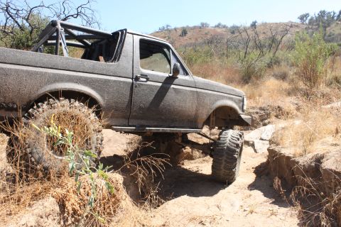 1992 Ford Bronco - This 1992 Ford Bronco is navigating a challenging off-road trail with large tires and a lifted suspension.