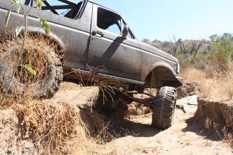 1992 Ford Bronco - This 1992 Ford Bronco is navigating a challenging off-road trail with large tires and a lifted suspension.