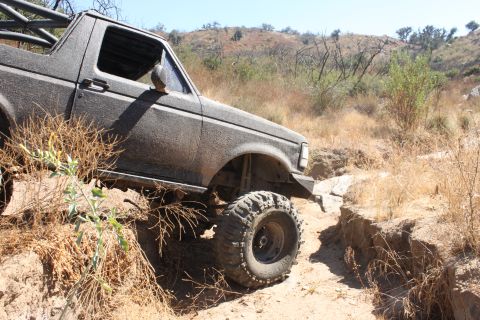 1992 Ford Bronco - An off-road vehicle is shown traversing a challenging, dry, and rocky terrain.