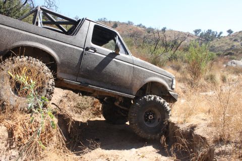 1992 Ford Bronco - This 1992 Ford Bronco is shown navigating a challenging dirt trail with its roll cage visible.