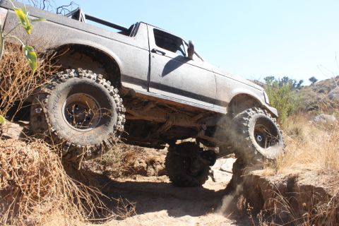 1992 Ford Bronco - A heavily modified off-road vehicle navigates a challenging dirt trail.