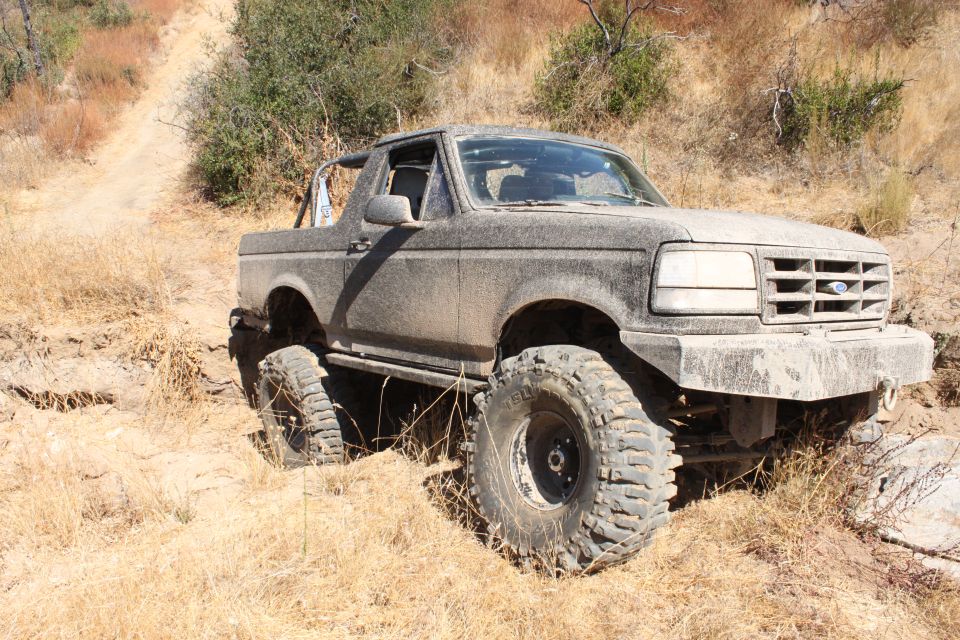 1992 Ford Bronco with large tires on a dirt trail