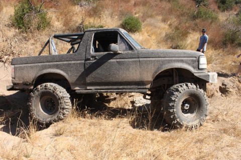 1992 Ford Bronco - A heavily modified Ford Bronco sits on a dry, grassy hillside, ready for off-road adventure.