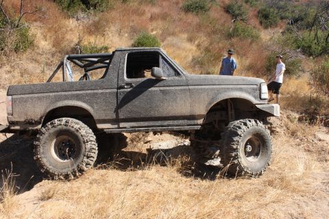 1992 Ford Bronco - This lifted 1992 Ford Bronco navigates a muddy trail, its off-road capabilities.