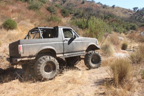 1992 Ford Bronco - This modified 1992 Ford Bronco navigates a , dry, and grassy trail, its off-road capabilities with a prominent roll cage and oversized tire…
