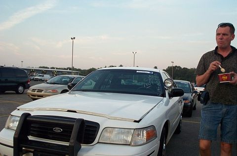 2001 Ford Crown Victoria - A white Ford Crown Victoria ex-police sedan with a black push bumper, A-pillar spotlight and soaped windshield price sits in an auction or…