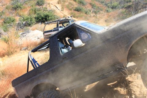 1992 Ford Bronco - Two off-road vehicles navigate a steep, dusty trail in a dry, scrubby environment.