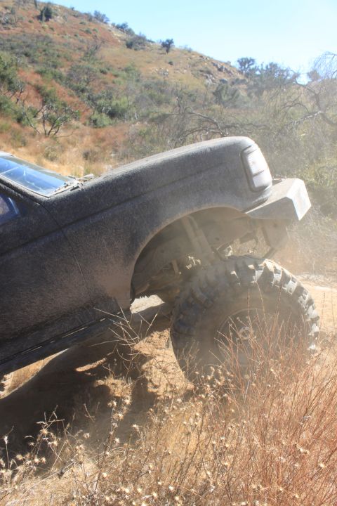 1992 Ford Bronco - A 1992 Ford Bronco navigates a dusty, off-road trail with significant suspension articulation.