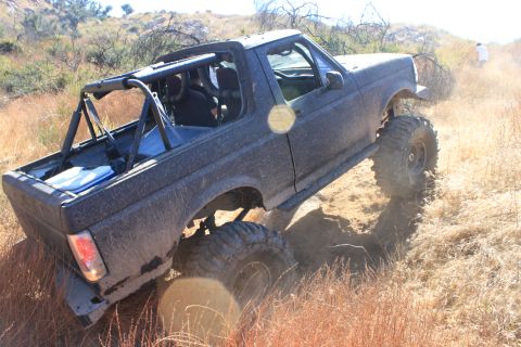 1992 Ford Bronco - This 1992 Ford Bronco navigates a dusty, off-road trail with its roll cage visible.